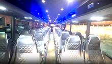 Interior of a bus with rows of seats and blue lighting.